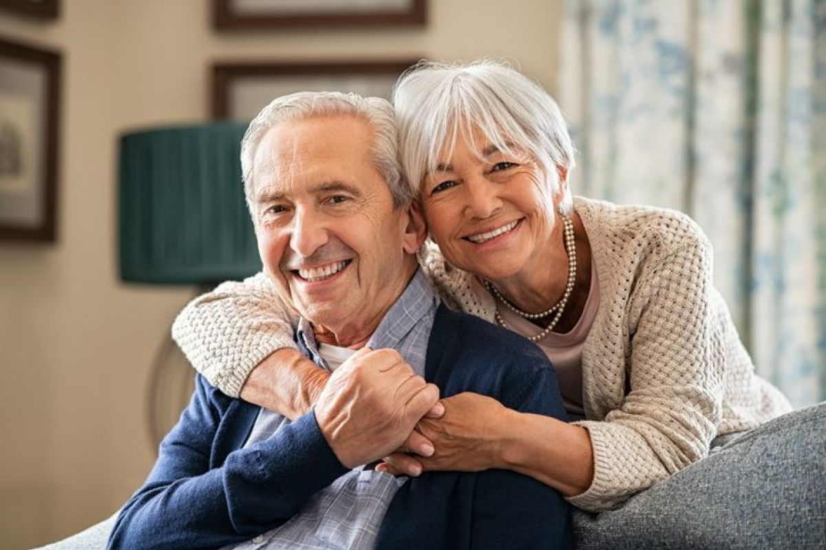 Lotterie-Gewinn - Glückliches älteres Ehepaar umarmt sich zuhause