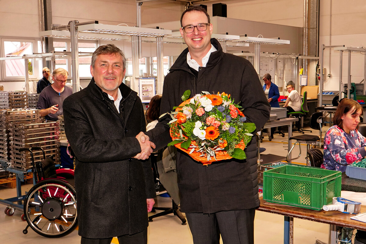 Axel Gloeckle mit den Backnanger Werkstätten, die ihm einen Blumenstrauß überreichen und sich freudig für die Spende bedanken.