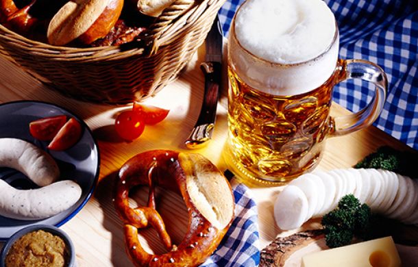 Tisch gedeckt mit einem Maß Bier, einer Brezel und Weißwürsteln.