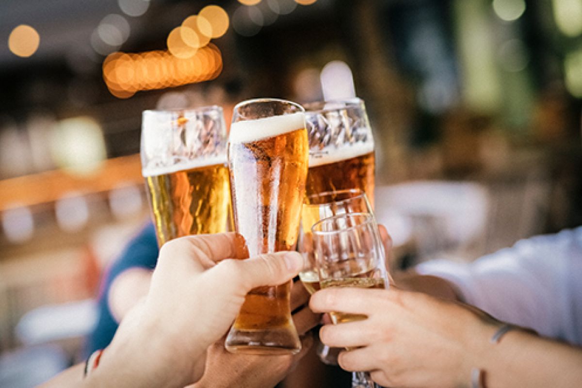 Mehrere Personen stoßen mit vollgefüllten Biergläsern an, um gemeinsam zu feiern.