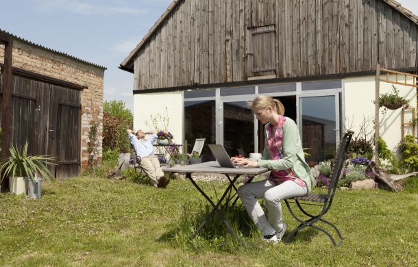 Eine Frau benutzt einen Laptop und frühstückt in ihrem Hinterhof.