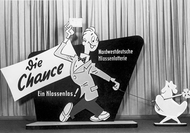 Pappschild zur Nordwestdeutschen Klassenlotterie, mit einer männlichen Figur, die ein Los in der Hand hält.