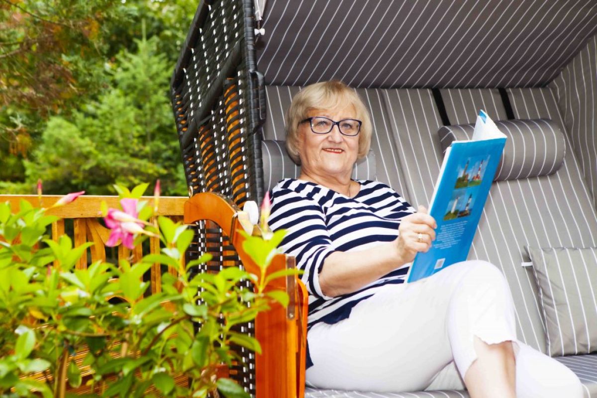 SKL Gewinnerin sitzt entspannt in ihrem Garten in einem Strandkorb und liest die Zeitung.