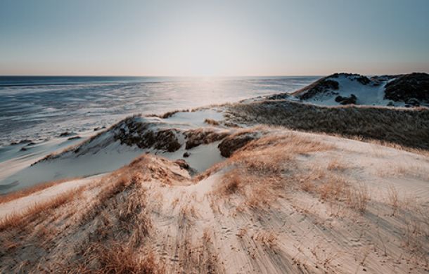 Ein malerischer Strand am Meer, mit sanften Wellen und Hügeln im Hintergrund.