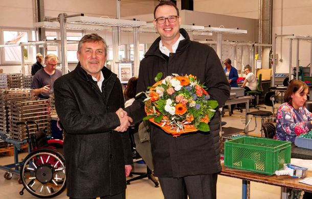 Axel Gloeckle mit den Backnanger Werkstätten, die ihm einen Blumenstrauß überreichen und sich freudig für die Spende bedanken.