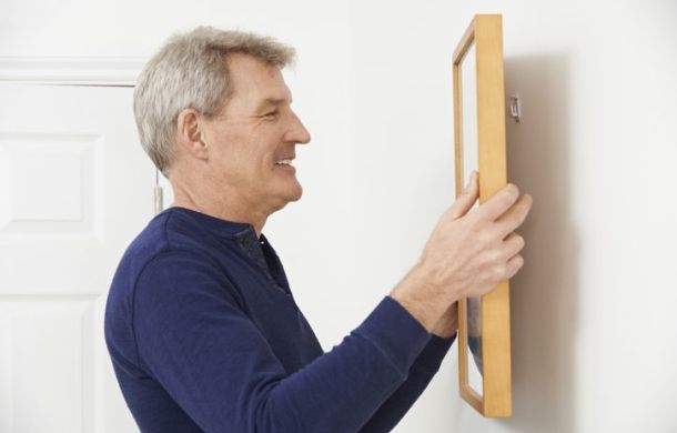 Ein Mann rahmt stolz seinen Kontoauszug mit seinem Lotteriegewinn ein und hängt ihn an die Wand.