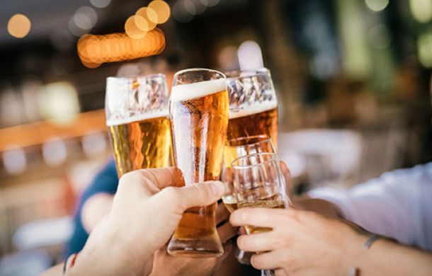 Mehrere Personen stoßen mit vollgefüllten Biergläsern an, um gemeinsam zu feiern.