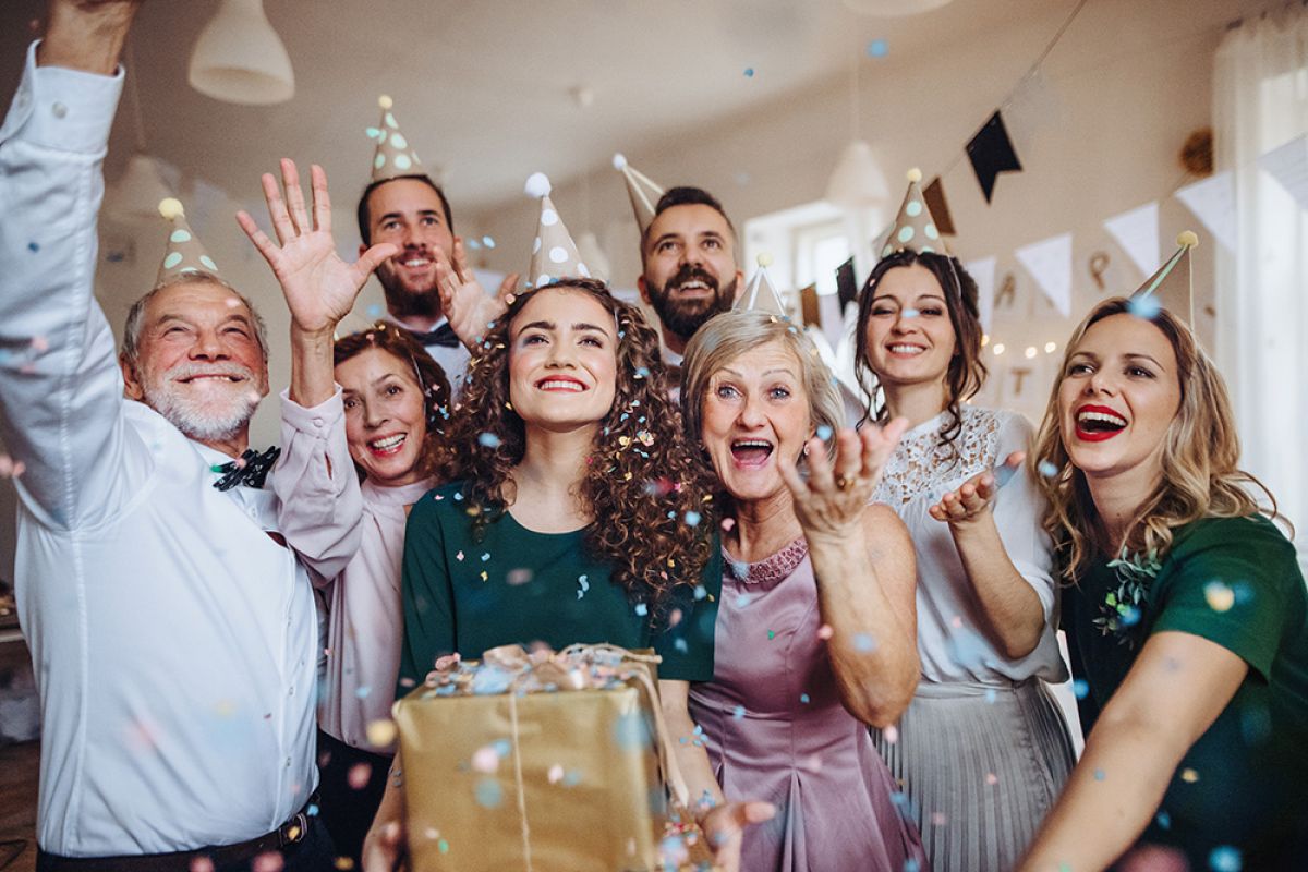 Ein Porträt einer Mehrgenerationenfamilie mit Geschenken, die auf einer Geburtstagsfeier im Haus stehen.