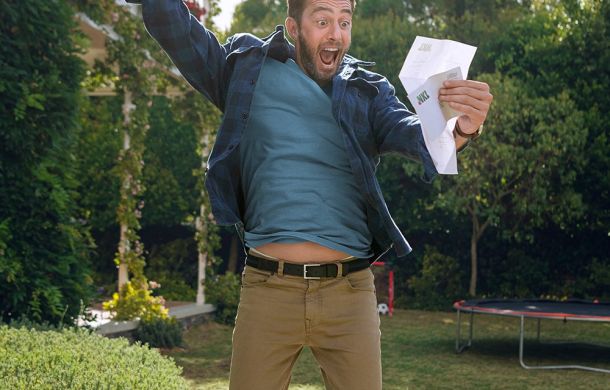 Mann springt vor Freude und hält ein Schreiben in der Hand, das seinen Gewinn bei der NKL bestätigt.