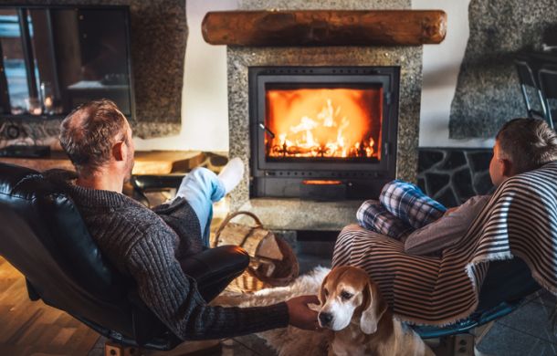 Vater und Sohn sitzen in bequemen Sesseln in ihrem Landhaus nahe dem Kamin und genießen die warme Atmosphäre.
