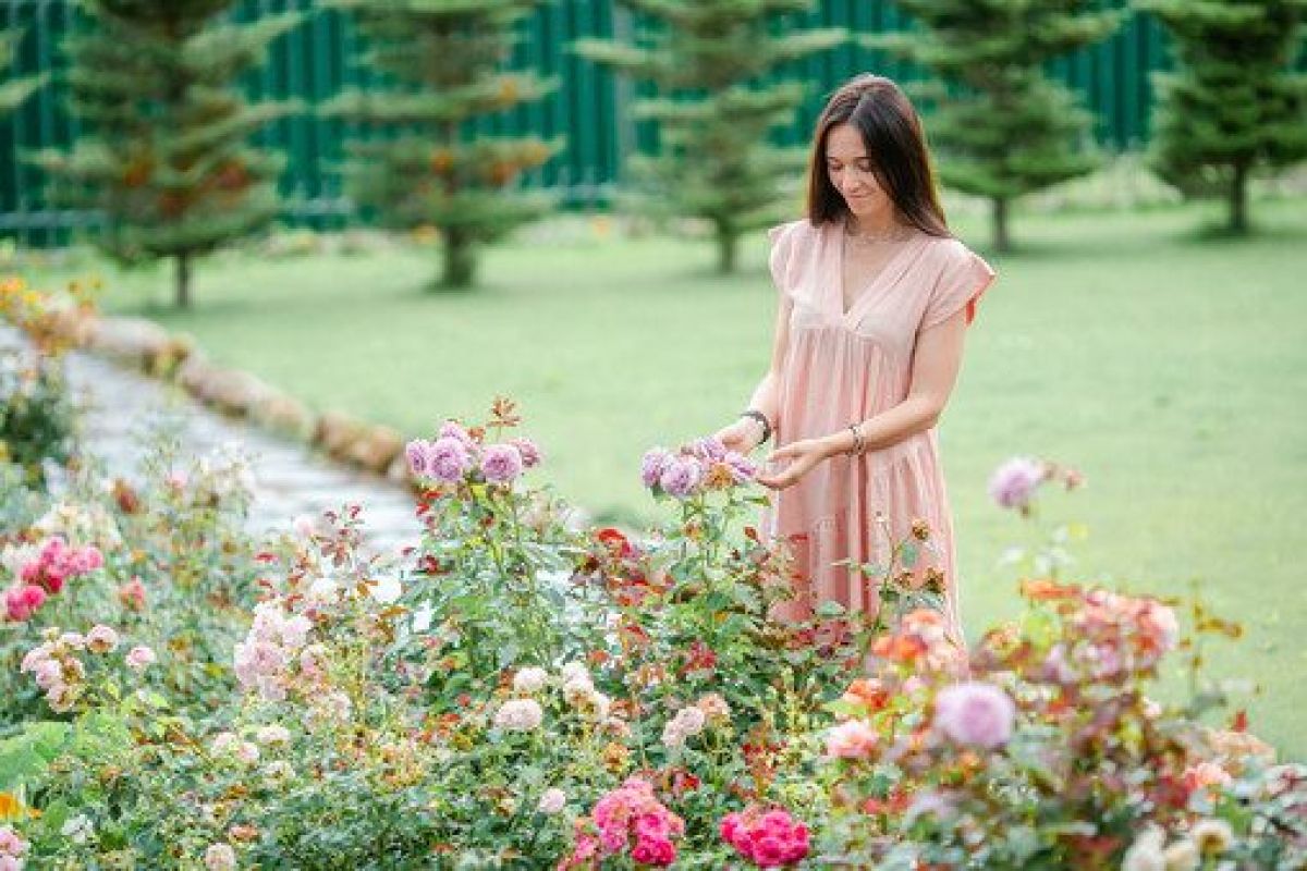 Junges Mädchen in einem Blumengarten zwischen wunderschönen Rosen.