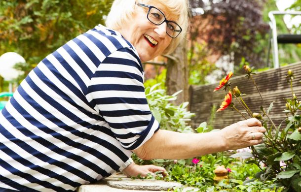 Eine ältere Frau im Garten, die sich um ihre Blumen kümmert.