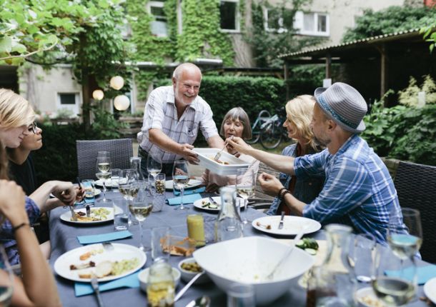 Familie sitzt an einem Tisch und genießt eine Mahlzeit, während sie gemeinsam am Grillen sind.