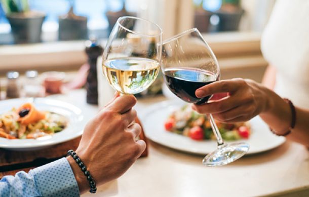 Junges Paar stößt fröhlich mit zwei Gläsern Wein an und feiert gemeinsam.