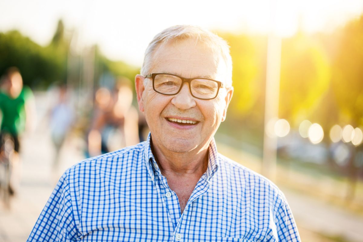 Outdoor-Portrait eines glücklichen älteren Mannes, der in die Kamera schaut und lächelt.